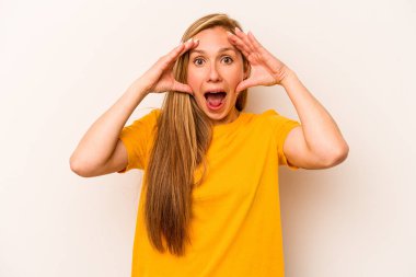 Beyaz arka planda izole genç beyaz kadın hoş bir sürpriz alıyor, heyecanlı ve el kaldırıyor..