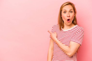 Pembe arka planda izole edilmiş genç beyaz kadın yan tarafı gösteriyor.