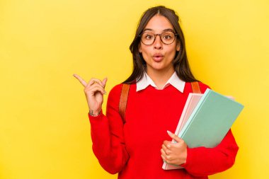 Sarı arka planda izole edilmiş genç bir İspanyol öğrenci yan tarafı işaret ediyor.