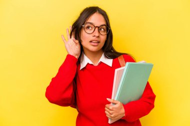 Genç İspanyol öğrenci, sarı arka planda izole edilmiş bir şekilde bir dedikoduyu dinlemeye çalışıyor..