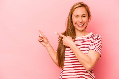 Pembe arka planda izole edilmiş genç beyaz kadın işaret parmaklarıyla fotokopi alanını işaret ederek heyecan ve arzusunu ifade ediyor..