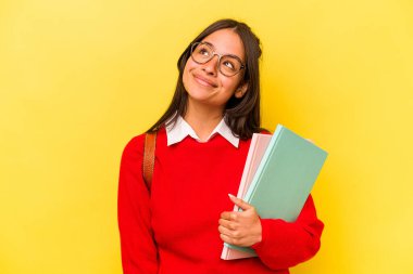 Genç İspanyol öğrenci, sarı arka planda izole edilmiş hedeflere ve amaçlara ulaşma hayali kuruyor.