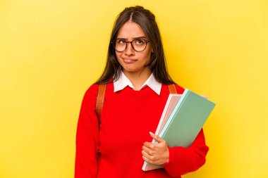 Sarı arka planda izole edilmiş genç İspanyol kadın kafası karışmış, kuşkulu ve güvensiz hissediyor..