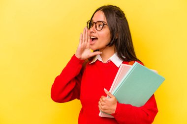 Sarı arka planda izole edilmiş genç İspanyol kadın bağırıyor ve avuç içini açık tutuyor..