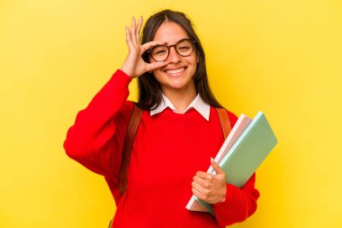 Genç İspanyol öğrenci, sarı arka planda izole edilmiş. Heyecanlı..