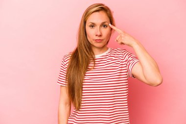 Pembe arka planda izole edilmiş beyaz bir kadın şakağı parmağıyla işaret ediyor, düşünüyor ve bir göreve odaklanıyor..