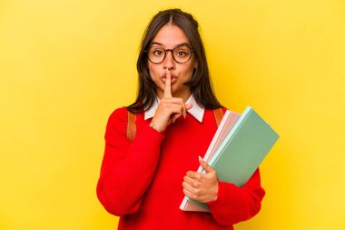 Genç İspanyol öğrenci, sarı arka planda izole edilmiş bir şekilde sır saklıyor ya da sessizlik istiyor..