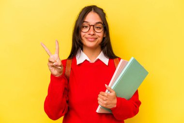 Sarı arka planda izole edilmiş genç İspanyol kadın iki numarayı parmaklarıyla gösteriyor..