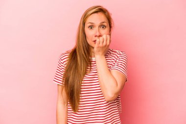 Pembe arka planda izole edilmiş, tırnak yiyen, gergin ve endişeli bir beyaz kadın..