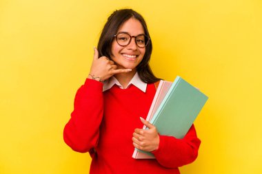 Sarı arka planda izole edilmiş genç İspanyol bir bayan cep telefonu hareketini parmaklarıyla gösteriyor..