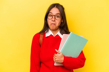 Genç İspanyol öğrenci, sarı arka planda izole edilmiş omuzlarını silker ve gözleri açık kalır..