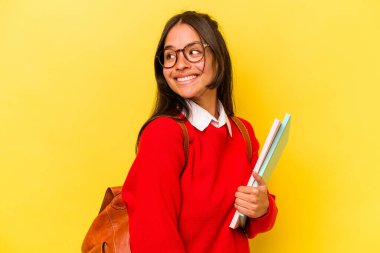 Sarı arka planda izole edilmiş genç bir İspanyol öğrenci gülümsüyor ve keyifli görünüyor..