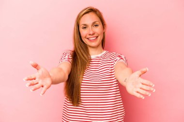 Pembe arka planda soyutlanmış beyaz bir kadın hoş bir yüz ifadesi sergiliyor..