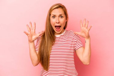 Pembe arka planda izole edilmiş genç beyaz kadın gökyüzüne haykırıyor, yukarı bakıyor, hayal kırıklığına uğramış..