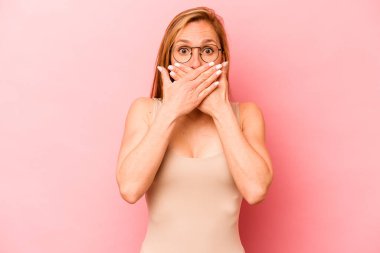 Pembe arka planda izole edilmiş beyaz bir kadın elleriyle ağzını kapatırken şok oldu..