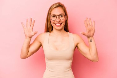 Pembe arka planda izole edilmiş genç beyaz kadın on numarayı elleriyle gösteriyor..