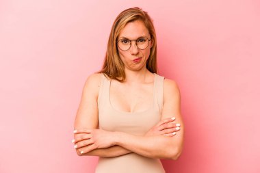 Pembe arka planda izole edilmiş genç beyaz kadın alaycı bir ifadeyle kameraya bakıyor..