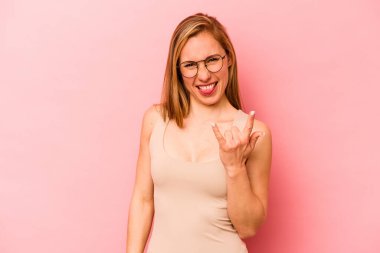 Pembe arka planda izole edilmiş genç beyaz kadın parmaklarıyla taş hareketi gösteriyor.