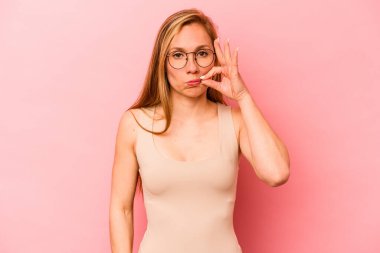 Pembe arka planda izole edilmiş genç beyaz kadın parmakları dudaklarında bir sır saklıyor..
