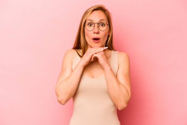 Pembe arka planda izole edilmiş genç beyaz bir kadın şans için dua ediyor, hayrete düşüyor ve ağzını açıp önüne bakıyor..