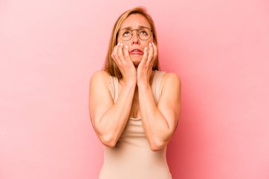 Pembe arka planda izole edilmiş beyaz bir kadın ağlıyor, bir şeyden mutsuz, acı ve kafa karışıklığı konsepti..