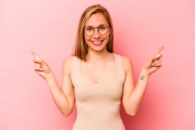Pembe arka planda izole edilmiş genç beyaz kadın farklı kopya alanlarını gösteriyor, birini seçiyor, parmağıyla gösteriyor..