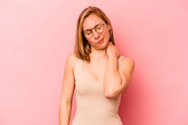 Pembe arka planda izole edilmiş genç beyaz kadın stresten dolayı boynu ağrıyor, masaj yapıyor ve elle dokunuyor..