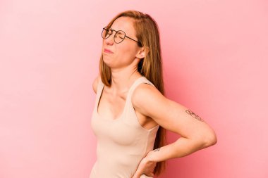 Pembe arka planda izole edilmiş beyaz bir kadın sırt ağrısı çekiyor..