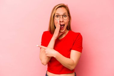 Pembe arka planda izole edilmiş genç beyaz bir kadın bir dedikodu söylüyor, bir haber sunuyor..