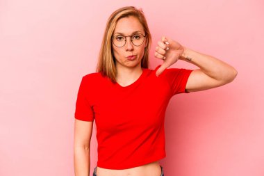 Pembe arka planda izole edilmiş genç beyaz bir kadın hoş olmayan bir jest gösteriyor. Anlaşmazlık konsepti.