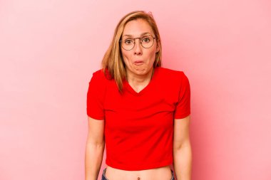 Pembe arka planda soyutlanmış beyaz bir kadın omuzlarını silkeliyor ve gözleri açık..