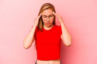 Genç beyaz kadın pembe arka planda izole edilmiş tapınaklara dokunuyor ve baş ağrısı çekiyor..