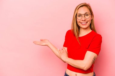 Pembe arka planda izole edilmiş genç beyaz kadın bir avuç içinde fotokopi alanı ve belinde bir el daha gösteriyor..