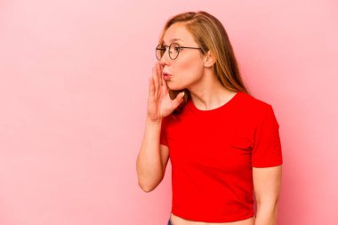 Pembe arka planda izole edilmiş genç beyaz kadın gizli bir sıcak fren haberi veriyor ve yana bakıyor.
