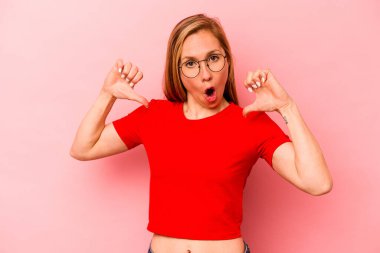 Pembe arka planda izole genç beyaz kadın gururlu ve kendinden emin hissediyor, örnek olarak..