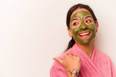 Yüz maskesi takan genç İspanyol kadın beyaz arka plan noktalarına izole edilmiş başparmak uzakta, gülüyor ve kaygısız..