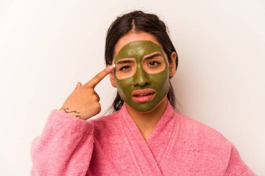 Beyaz arka planda izole edilmiş yüz maskesi takan genç İspanyol kadın işaret parmağıyla yaptığı hayal kırıklığı jestini gösteriyor..