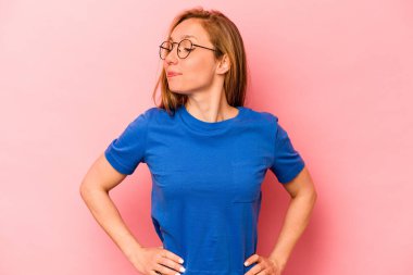 Pembe arka planda izole edilmiş genç beyaz kadın hedeflere ve amaçlara ulaşma hayali kuruyor.