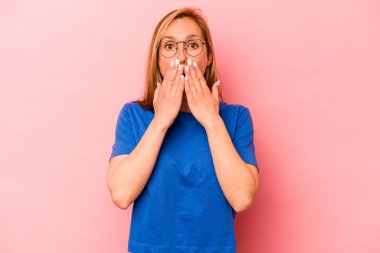 Pembe arka planda izole edilmiş beyaz bir kadın elleriyle ağzını kapatırken şok oldu..