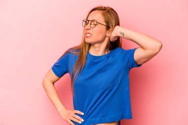 Pembe arka planda izole edilmiş genç beyaz kadın yorgun ve uykulu ellerini başının üstünde tutuyor..