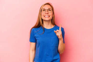 Pembe arka planda izole edilmiş genç beyaz kadın iki parmağı da boş bir alan gösteriyor..