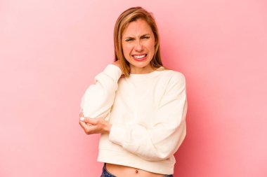 Genç beyaz kadın pembe arka planda izole edilmiş dirsek masajı yapıyor, kötü bir hareketin ardından acı çekiyor..