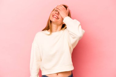 Pembe arka planda soyutlanmış beyaz bir kadın ellerini başının üstünde tutarak neşe içinde gülüyor. Mutluluk kavramı.