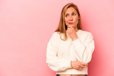 Pembe arka planda soyutlanmış beyaz bir kadın şüpheli ve şüpheci bir ifadeyle yana bakıyor..