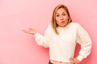 Pembe arka planda izole edilmiş genç beyaz kadın bir avuç içinde fotokopi alanı ve belinde bir el daha gösteriyor..