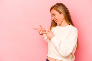 Pembe arka plan noktalarında izole edilmiş genç beyaz kadın başparmak uzakta, gülüyor ve kaygısız..