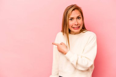 Pembe arka planda izole edilmiş genç beyaz kadın yan tarafı gösteriyor.