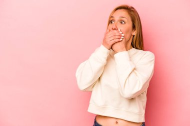 Pembe arka planda izole edilmiş beyaz bir kadın. Düşünceli bir şekilde ağzıyla ağzını kapatan bir fotokopi odasına bakıyor..