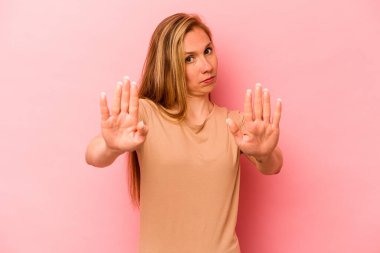 Pembe arka planda izole edilmiş genç beyaz kadın elini uzatmış, dur işareti göstererek seni engelliyor..