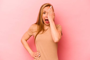 Pembe arka planda izole edilmiş beyaz bir kadın yüzünün yarısını palmiye ile örterek eğleniyor..